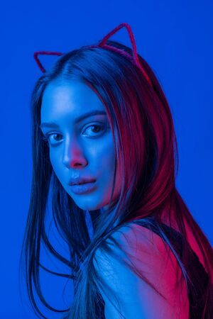 High Fashion model woman in colorful bright lights posing in studio, portrait of beautiful sexy girl with trendy make-up. Art design, colorful make up. Over colourful vivid background. Cat-girlの写真素材