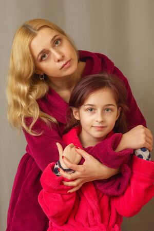 Mom and daughter in warm bathrobes. warm relations between mother and daughter. spend time together. body care . are pointed at the camera. picture for memory. Elegant mothe with little daughter.の写真素材