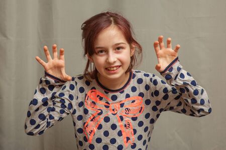 Beautiful young girl in pajamas. Girl in pajamas. Girl 9 years old in a gray dress with blue polka dots on a gray background. The girl is getting ready to go to sleep.Girl with tinted hair 9 years oldの写真素材