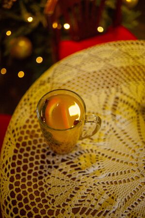autumn and winter hot tea with cinnamon and orange . Warming drink and a warm knitted sweater. Winter tea with cinnamon and orange. Tea on the background of the New Year tree. Christmas concept.の写真素材