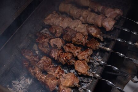 Close-up of grilling tasty dish on barbecue. Process of cooking yummy shashlik in nature. Delicious food on metal skewer in bbq. Time to picnic conceptの写真素材