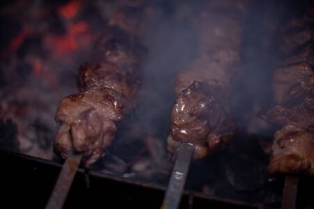Close-up of grilling tasty dish on barbecue. Process of cooking yummy shashlik in nature. Delicious food on metal skewer in bbq. Time to picnic conceptの写真素材
