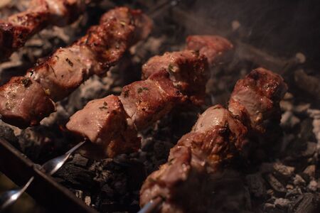 Close-up of grilling tasty dish on barbecue. Process of cooking yummy shashlik in nature. Delicious food on metal skewer in bbq. Time to picnic concept. Street food. Food festival. Pork at the stakeの写真素材