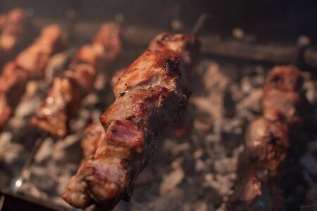 Close-up of grilling tasty dish on barbecue. Process of cooking yummy shashlik in nature. Delicious food on metal skewer in bbq. Time to picnic concept. Street food. Food festival. Pork at the stakeの写真素材