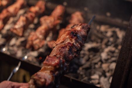 Close-up of grilling tasty dish on barbecue. Process of cooking yummy shashlik in nature. Delicious food on metal skewer in bbq. Time to picnic concept. Street food. Food festival. Pork at the stakeの写真素材