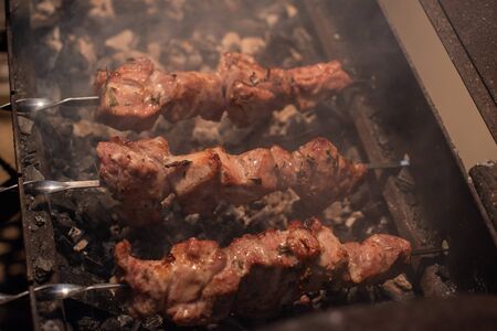 Close-up of grilling tasty dish on barbecue. Process of cooking yummy shashlik in nature. Delicious food on metal skewer in bbq. Time to picnic concept. Street food. Food festival. Pork at the stakeの写真素材
