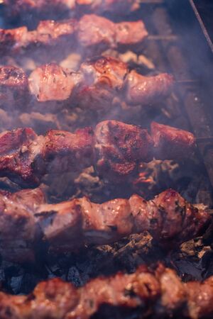 Close-up of grilling tasty dish on barbecue. Process of cooking yummy shashlik in nature. Delicious food on metal skewer in bbq. Time to picnic concept. Street food. Food festival. Pork at the stakeの写真素材