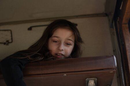 Cute girl lying on the top shelf in the train. Summer Vacation and Travel Concept. the girl in the train lies on the top shelf. A girl of 8 or 9 years old rides on a train. Teen travels. Summerの写真素材