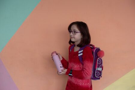 girl with cup. schoolgirl girl in glasses drinks water from a thermomug.A schoolgirl drinks tea,...