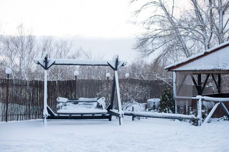 Wooden swing under the snow. Wooden swing in winter under the snow. Winter concept. Snowの写真素材