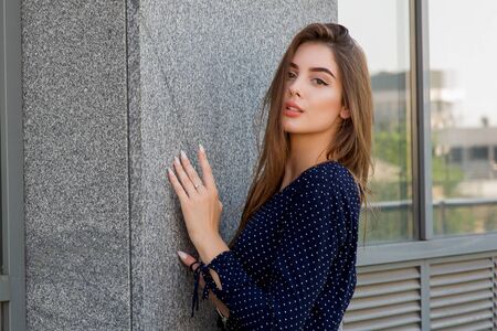 beautiful girl in a blue dress walks along the street on the background of a cafe. Girl in a blue...
