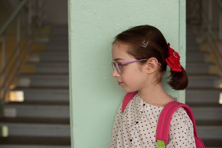 Girl 9 years old with a school backpack on her back. Portrait of a schoolgirl 9 years old. 4th grade school.Schoolgirl at school with a pink backpack. Back to school.9 years old girl in a white blouseの写真素材