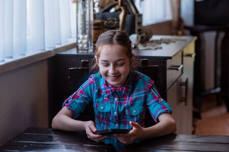 The Internet. Message. Girl in a cafe with a smartphone. The child looks in the smartphone. Gadgets...