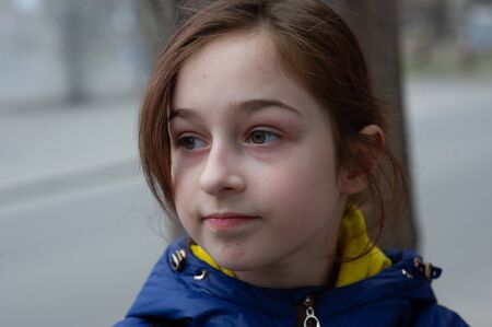 Beautiful young cute woman in blue coat is posing on urban city background. a blue jacket. 9 years...