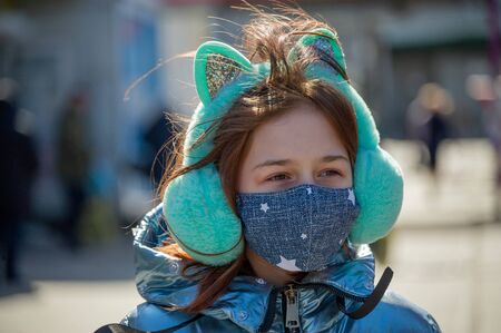 Woman in protective mask outdoors. Masked girl outdoors. Virus, mask, spring. Girl 9 years old. Street. Protection against viruses and bacteria. Medical respiratory mask. Epidemic. Protectionの写真素材