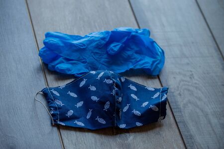 A protective half mask is lying on the table next to a pair of disposable gloves. Protective items...