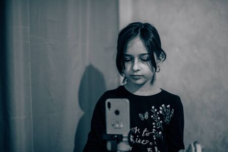 Happy young woman taking selfie on white background. Girl takes a video of herself with a monopod or selfie stick. Blogger. Vlog. The girl makes videos for the Internet or Internet networks. Portraitの写真素材