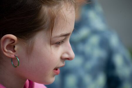 Beautiful young cute woman. 9 years old. Girl 9 years old on the street. 9 years old girl on the street. A teenager in a pink sweater with a hood. Spring, nature, peopleの写真素材
