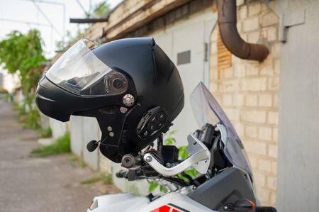 Motorcyclist's crash-helmet hanging on the handle of a motorcycle. Helmet hanging on the steering...