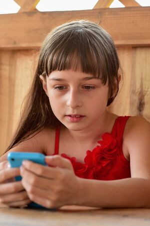 little girl looks at the phone. 8-9 years old girl looks into the phone. lifestyle portrait of sweet...