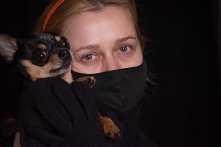Coronavirus, masked woman.Studio portrait of a young woman wearing a face mask, on black background....