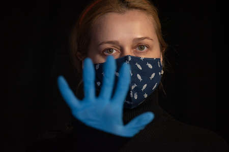 Coronavirus, masked woman.Studio portrait of a young woman wearing a face mask, on black background....