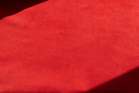 Red matte background of suede fabric, closeup. Velvet texture of seamless leather. Felt material...