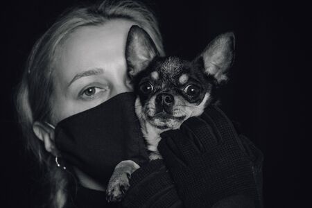 Woman in a protective mask. Young woman wearing home made hygienic face medical mask to prevent infection, illness or flu and 2019-nCoV. Black background. Protection against disease, coronavirus.の写真素材