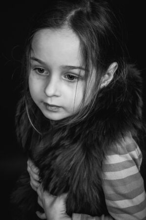 Beautiful girl doing different expressions: arms raised. Little girl on a black background. Portrait of a child. Emotional child.の写真素材