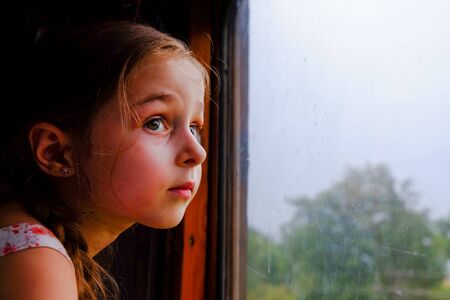 Cute girl in the train. Summer Vacation and Travel Concept. A girl of 5 or 6 years old rides on a train. Teen travels. Little girl with long hair. Child portraitの写真素材