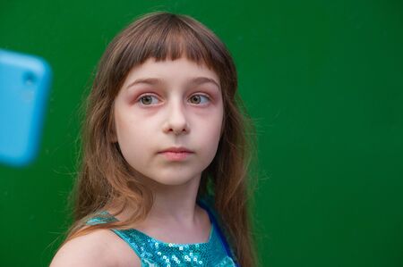 Cute little girl using smartphone on green background. Little girl takes a selfie. Alpha Generation Millennial Children - Active Internet Users. generation Z.の写真素材