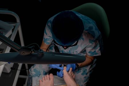 Professional pedicure in the beauty salon. The beautician cuts the skin with fingernails and performs professional pedicure. Podology treatment. Podiatrist. Health, body care concept.の写真素材
