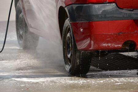 red car during washing process. transport in foam at a car wash. Manual car wash with pressurized...