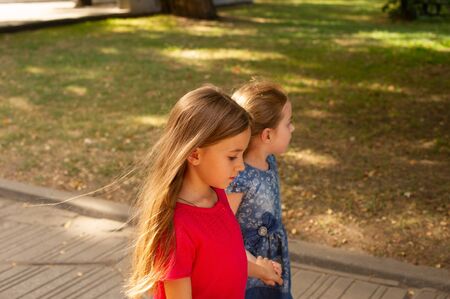 Sisters, Outdoor photo from two little girls. Two little girls walk in the park by the hand. Sisters for a walk in the summer or autumn on the street. Girlfriends, children, nature. Family concept.の写真素材