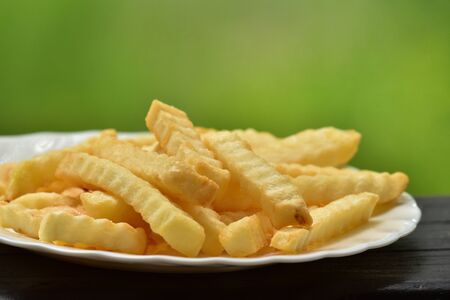 Fast food french fries on summer terrace or cafe. french fries on rustic rosemary and spices in a...