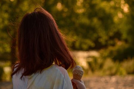 Beautiful little girl eats ice-cream in the summer. girl eating ice cream. 9 years old girl walking...