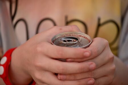 Young girl drink water. Teen girl drinks with an iron can. A 9-year-old girl holds a drink in her hands.の写真素材