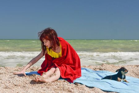 Girl 9 years old at sea. The portrait of the young girl about 9-12 years old. Teenager summer vacation sand. Girl and dog. Chihuahua. Childhood travel vacation. Little girl rejoices in pestilence.の写真素材