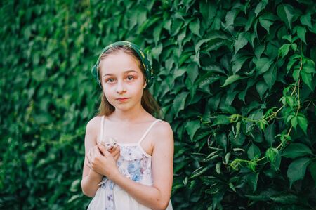 Child holding baby cat. Kids and pets. Little girl hugging cute little kitten in summer garden. Domestic animal in family with kids. Children with home pet animals. Girl and little kitten. 9 years oldの写真素材