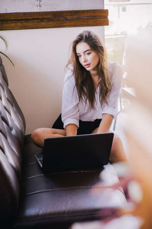 Young beautiful business woman working on a laptop. Beautiful girl in a white shirt at the computer....