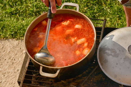 Cast-iron cauldron with soup at the stake in the courtyard. Summer day and dinner in the fresh air...