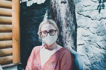 Woman in a protective mask with tissue. Young woman in a protective mask. Girl in a swimsuit on vacation in a protective mask from viruses. Virus, protection, health. Epidemic, medicine. allergiesの写真素材