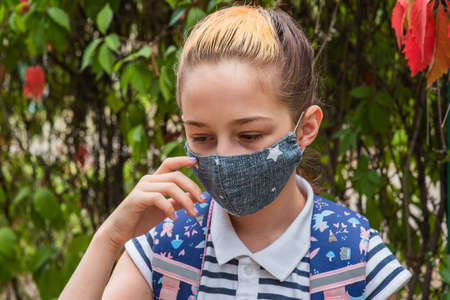 Schoolgirl girl in a protective mask with a backpack. Schoolgirl in a school uniform. Fall. Back to...