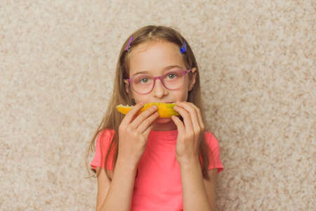 Portrait of girl biting melon. Girl eating melon. Teenager in pink t-shirt at home. Healthy food, vitaminsの写真素材