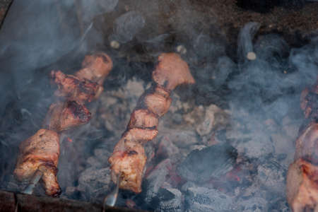 Grilled kebab cooking on metal skewer closeup. Roasted meat cooked at barbecue. BBQ fresh beef meat chop slices. Traditional eastern dish, shish kebab. Grill on charcoal and flame, picnic, street foodの写真素材