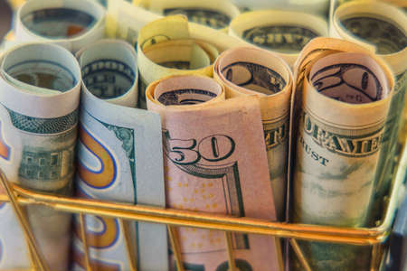 Supermarket grocery push cart for shopping with bundle of dollars money banknote cash. Dollars in...