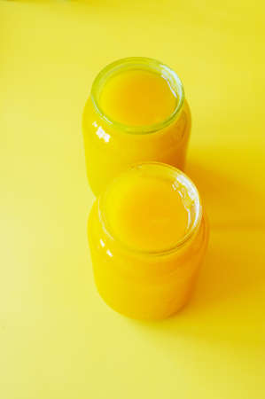 two jars of honey on yellow background. Two jars of honey. Healthy food, organic food, nutrition, vegetarian. Honey isolated on yellow backgroundの写真素材