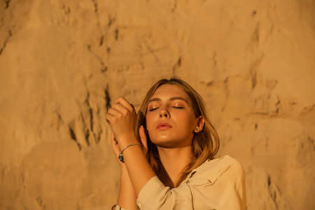 Girl on the background of sands. Portrait of a girl. Young girl with long blond natural hair in...