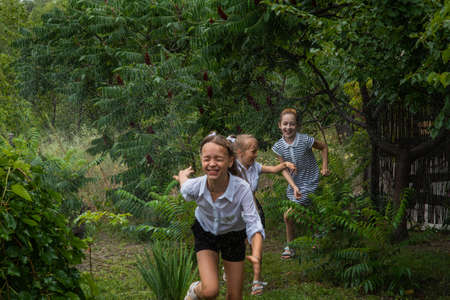 Three girls schoolgirls in the rain. Schoolgirls run in the rain in warm weather. Three girlfriends