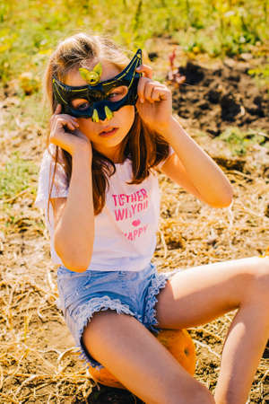 Teenager girl and pumpkin in the vegetable garden. A girl with a pumpkin wearing glasses for Halloween. Halloween, autumnal feast, autumn. Harvesting in autumnのeditorial素材